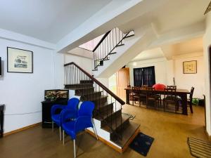 a living room with a staircase and blue chairs at Ranmin Cottages A5 in Nuwara Eliya