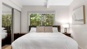 Un dormitorio blanco con una cama grande y dos ventanas. en Stone Lagoon by AvantStay Steps to the Beach Backyard Oasis, en San Clemente