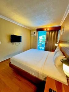 a bedroom with a large white bed and a television at Roman Empire Panglao Boutique Resort in Bohol-Panglao International Airport
