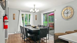 a dining room with a table and chairs and a clock at Lakeside Haven Ping Pong Fire Pit Mins to Big Boulder Lake Harmony in Lake Harmony