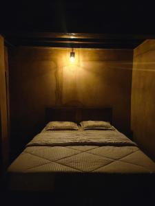a bed in a dark room with a light on it at Aravanazhi tharavadu in Thirunelli