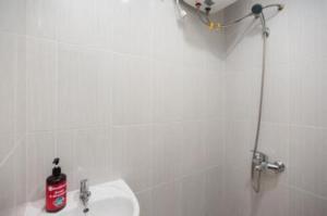 a white bathroom with a sink and a shower at Hanna Residence near RSPI Puri Indah Mitra RedDoorz in Meruya-hilir