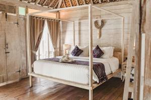 a bedroom with a canopy bed with white sheets and pillows at Java Wood in Gili Trawangan