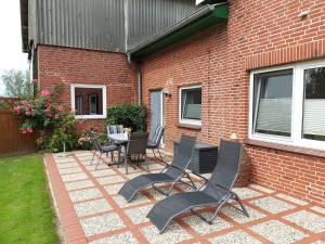 Un patio con sillas y una mesa frente a un edificio de ladrillo. en Ferienhof Friedenshof Hafer, en Vollerwiek