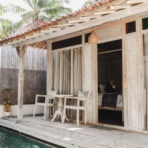 a porch with a table and chairs next to the water at Java Wood in Gili Trawangan