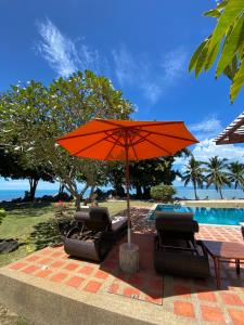 an orange umbrella and chairs next to a pool at Baan Laem Noi Villa's in Mae Nam