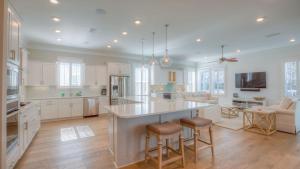 a kitchen with white cabinets and a large island with bar stools at Coconut Cove by AvantStay Deck w Hot Tub Access to 2 Pools in Santa Rosa Beach