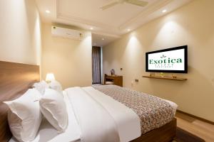 a bedroom with a white bed with a tv on the wall at Hotel Exotica Avenue - Business-Friendly Stay, Golf Course Road, Cyberhub, One Horizon Center & Metro in Gurgaon +62 photos