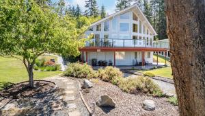 a large white house with a tree in front of it at Harborview Getaway by AvantStay Walk to Beach in Langley