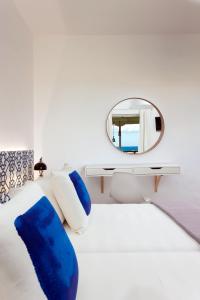 a bedroom with a white bed with blue pillows and a mirror at Galatea in Kypseli