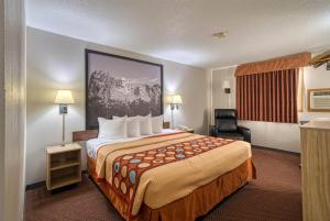 a hotel room with a large bed and a chair at Super 8 by Wyndham Hot Springs in Hot Springs +26 photos