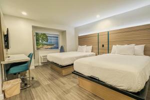 a hotel room with two beds and a chair at Baymont by Wyndham Henrietta - Rochester in Henrietta