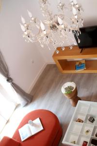 sala de estar con silla roja y lámpara de araña en PINTORES ROOMS Apartamentos Turísticos, en Cáceres
