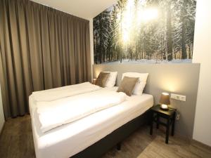 a bedroom with a white bed with a painting on the wall at Vogue Apartment in Sankt Margarethen im Lungau near Ski Lift in Sankt Margarethen im Lungau +87 photos
