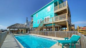 a house with a swimming pool next to a building at Waterfront w Bay Views Shared Pool Boat Dock Marlin Madness by AvantStay in Padre Island