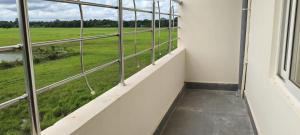 a balcony with a view of a green field at Luit Hotel in Majuli