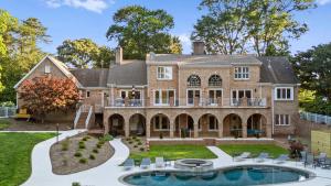 an exterior view of a large brick house with a swimming pool at Shoreway Cove by AvantStay Waterfront Pool Dock in Huntersville