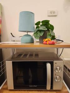 a microwave under a table with a lamp and a plant at Hawaii Theme Ortigas MRT Ayala 30th Megamall Podium Free Netflix Fast Internet Pool in Manila +15 photos