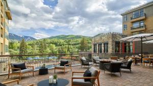 Un patio con mesas y sillas y un balcón con vistas a las montañas. en Beaver Creek Solace Resort Access with Pool Hot Tub Premier Avon Location, en Avon