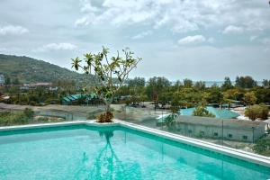 a large swimming pool with a tree in the middle at Fantasea Condo Kamala A210 2BDRM by Phuket Sabay Rent in Kamala Beach