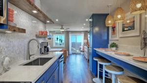 una cocina con armarios azules y una barra con taburetes en 2 Studios Beach Boardwalk 2 Pools TennisPickleball Island Retreat Complex, en Port Aransas