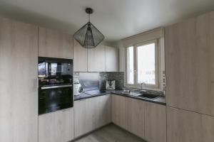 Una cocina con armarios de madera y un fregadero y una ventana. en Nice apartment with balcony in Pré-Saint-Gervais, en Le Pré-Saint-Gervais