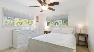 a white bedroom with a bed and a ceiling fan at Eagles Watch by AvantStay Large Deck w Views in Coupeville