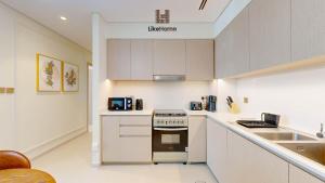 a kitchen with white cabinets and a stove top oven at Dubai Skyline Balcony Views near Burj Khalifa & Dubai Mall Luxury 2BR - Like Home in Dubai