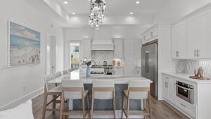 a white kitchen with a dining table and chairs at Pool Hot Tub Firepit Golf Cart Included Walk to Beach Near Gulf Place in Santa Rosa Beach