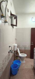 a bathroom with a toilet and two blue buckets at Atithi Home Stay- Studio Room in Udaipur