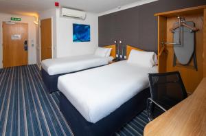 a hotel room with two beds and a desk at Holiday Inn Express Southampton West by IHG in Southampton