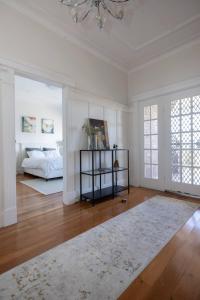a white bedroom with a bed and a chandelier at Private BB near airport, beach, and activities in Sydney