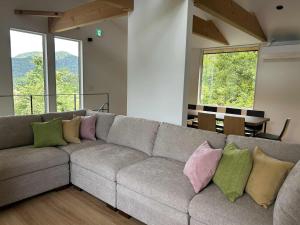 a living room with a gray couch with colorful pillows at Hakuba Mitsuki Chalet in Hakuba