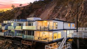 マリブにあるBig Rock Beach Retreat with Oceanfront Balconies Direct Beach Access Sweeping Sunset Views Pacific Coast Outlook by AvantStayの背後に丘がある水辺の家