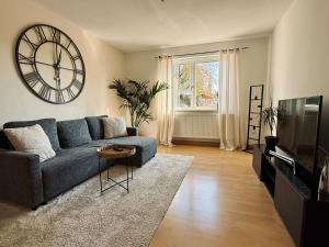 a living room with a blue couch and a large clock at Wohnen am Main in Würzburg