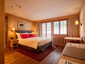 a bedroom with a bed with red pillows at Hotel Le Grand Chalet Gstaad in Gstaad