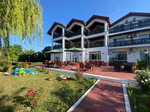 Băltenii de SusにあるHotel Welsの白い大きな建物で、テーブルと椅子付きのパティオが備わります。