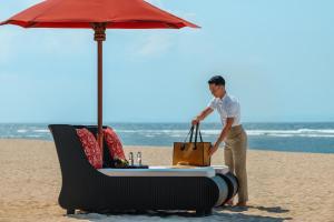 a man standing next to a table and an umbrella on the beach at The St. Regis Bali Resort in Nusa Dua