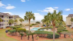 an aerial view of a resort with a swimming pool and palm trees at 202 D Port O Call by AvantStay Beach Condo in Isle of Palms