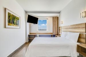 a bedroom with a large white bed and a window at One Guadalajara Periferico Norte in Guadalajara +25 photos