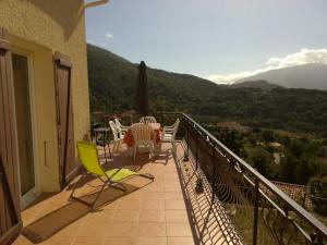 a balcony of a house with a table and chairs at 95m2 au calme à 25mn AJACCIO, plages, linge inclus parking ok in Ucciani