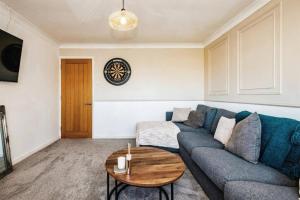 ein Wohnzimmer mit einem blauen Sofa und einem Holztisch in der Unterkunft Modern coastal 1 bed flat in Shoreham in Lancing