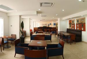 a restaurant with tables and chairs and a piano at One Guadalajara Centro Historico in Guadalajara