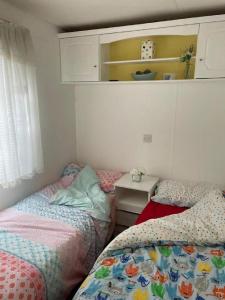 1 dormitorio con 2 camas y una mesa pequeña en Lovely Caravan With Large Decking Area At Southview Ref 33179S, en Winthorpe