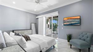 a white bedroom with a bed and a chair at Marco Polo by AvantStay Waterfront 5BDR Pool Spa Fire Pit Walk to Beach in Marco Island +44 photos