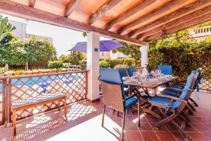 a patio with a table with chairs and an umbrella at Villa Ewa by Slow Villas in Cala Pi