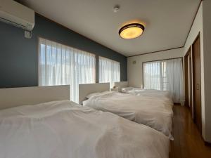Dos camas blancas en una habitación con ventana. en UMI&kanzanji, en Hamamatsu