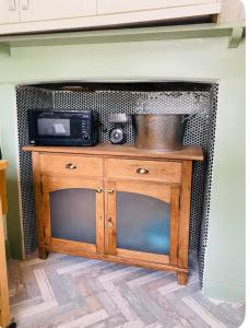 a wooden cabinet with a microwave on top of it at The Hideaway in Sutton Scotney