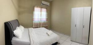 SandakanにあるAtiya Homestay Sandakanの白いシーツと窓のあるベッドのある寝室 +5枚の写真