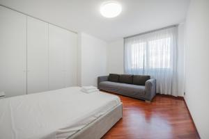 Cette chambre blanche dispose d'un lit et d'un canapé. dans l'établissement Ca' Nina - 15 min from Venice & Free Parking, à Venise
